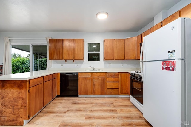 kitchen featuring dishwasher, a sink, freestanding refrigerator, range with gas stovetop, and a peninsula