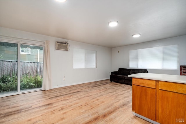 living area featuring light wood-style flooring, baseboards, and a wall mounted air conditioner