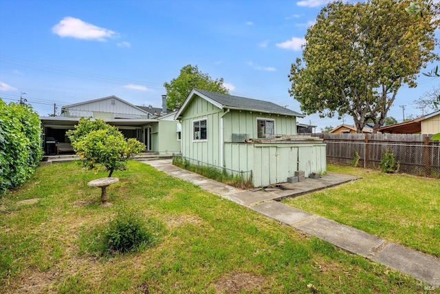 exterior space featuring board and batten siding, a front yard, and fence