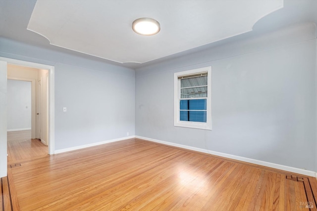 unfurnished room featuring visible vents, light wood finished floors, and baseboards