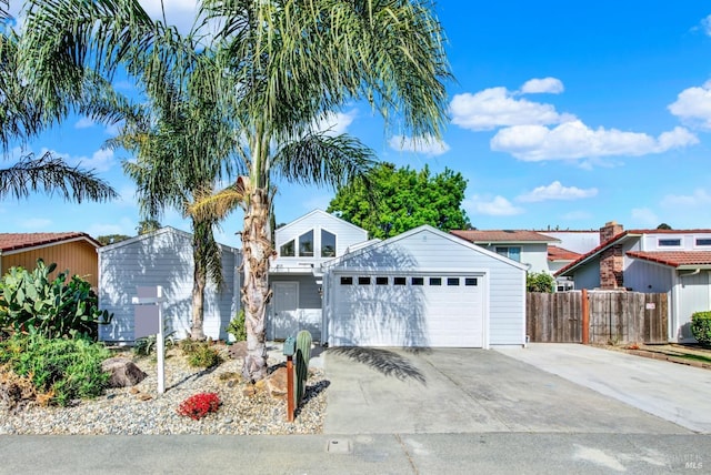 view of front of house with fence, an attached garage, and concrete driveway