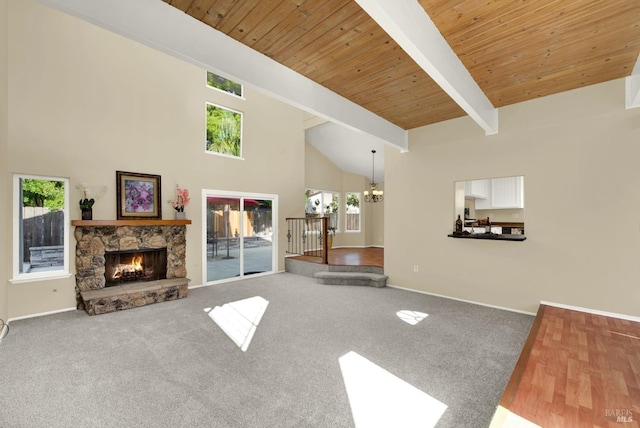 carpeted living room featuring a stone fireplace, a wealth of natural light, high vaulted ceiling, and an inviting chandelier