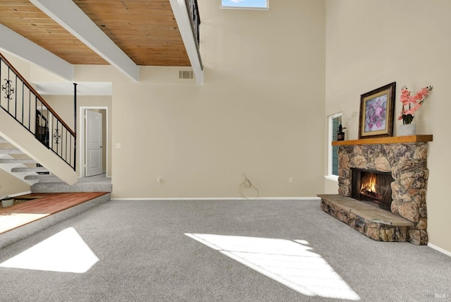 unfurnished living room with carpet flooring, visible vents, stairway, wooden ceiling, and a fireplace