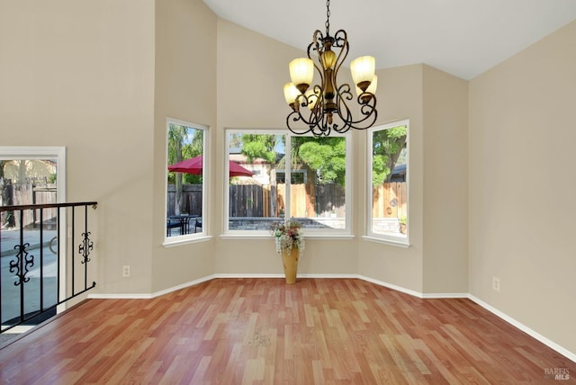 unfurnished room featuring vaulted ceiling, baseboards, a notable chandelier, and wood finished floors