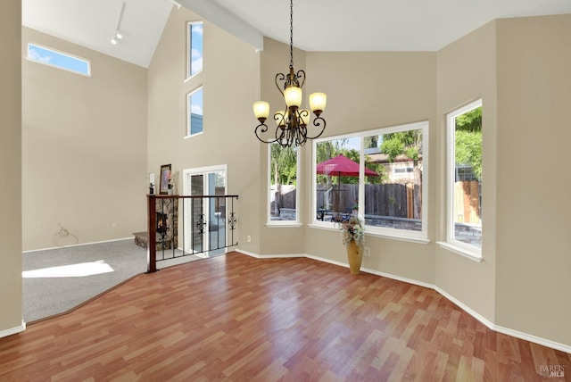unfurnished dining area with baseboards, a notable chandelier, and wood finished floors