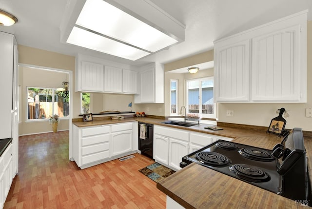 kitchen with light wood-type flooring, white cabinetry, a sink, and black appliances
