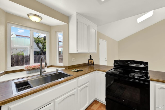kitchen featuring dark countertops, white cabinetry, black range with electric stovetop, and a sink