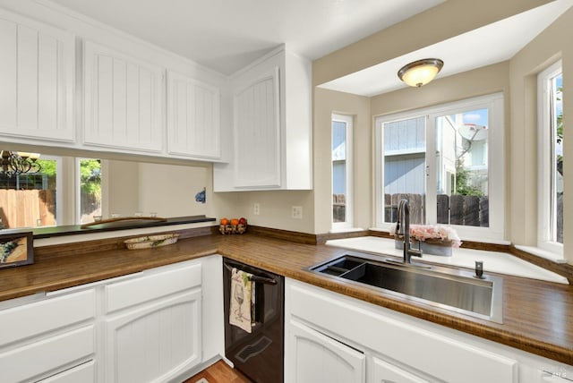 kitchen featuring white cabinets, wood counters, dishwasher, and a sink