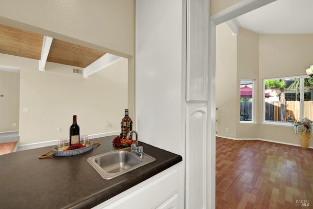 bar featuring lofted ceiling with beams, a sink, visible vents, wood finished floors, and indoor wet bar