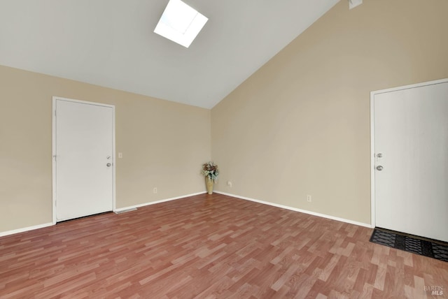 interior space with high vaulted ceiling, light wood-style flooring, a skylight, and baseboards