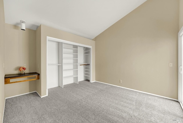 unfurnished bedroom featuring lofted ceiling, a closet, carpet flooring, and baseboards