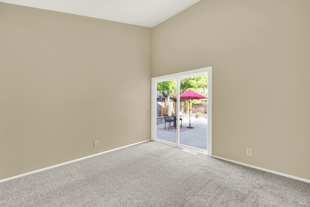 empty room with high vaulted ceiling, carpet floors, and baseboards