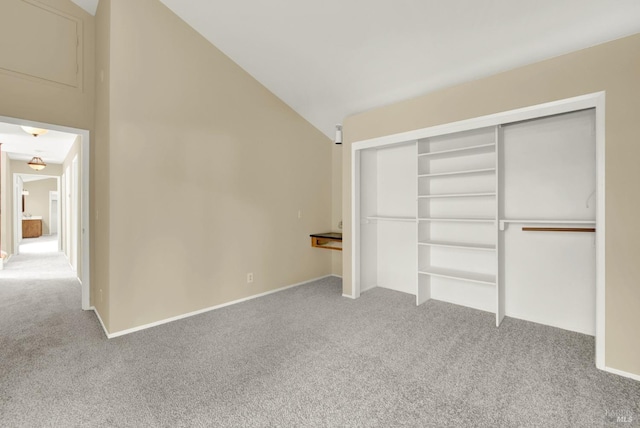 unfurnished bedroom with lofted ceiling, a closet, and carpet