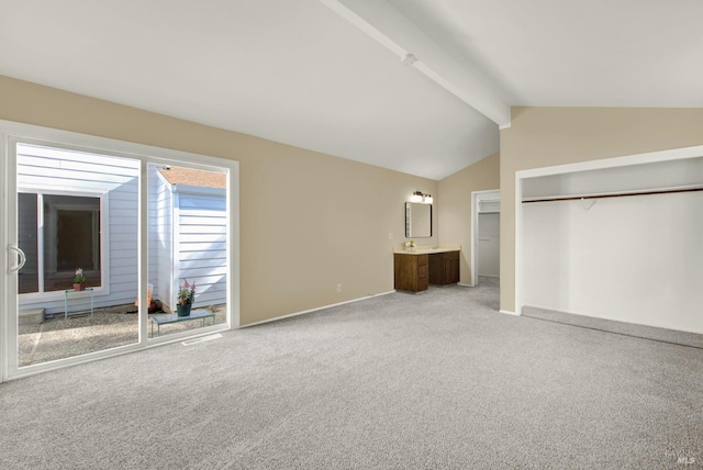 unfurnished bedroom with light carpet, vaulted ceiling with beams, a closet, and ensuite bathroom