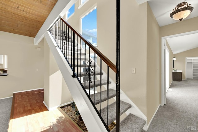 stairway featuring wooden ceiling, vaulted ceiling, carpet flooring, and baseboards