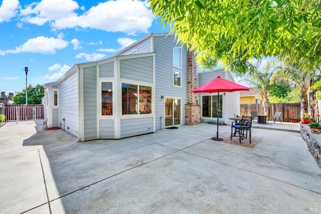 back of property with fence and a patio