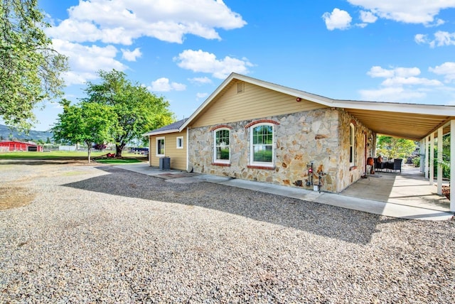 view of front of home featuring stone siding, a patio area, and cooling unit