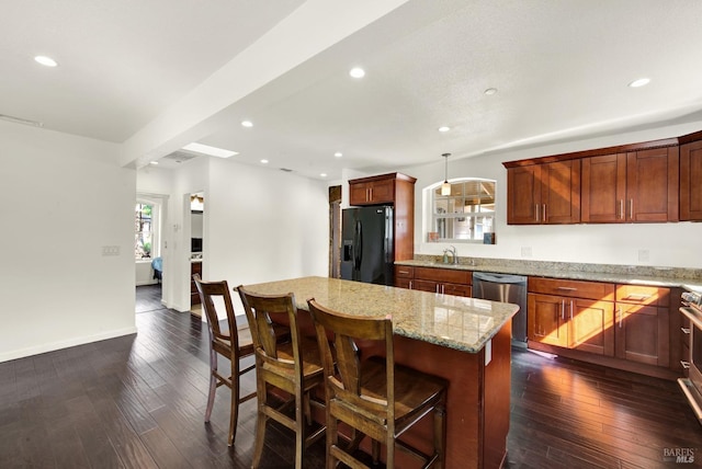 kitchen with a center island, appliances with stainless steel finishes, a sink, and dark wood-style floors