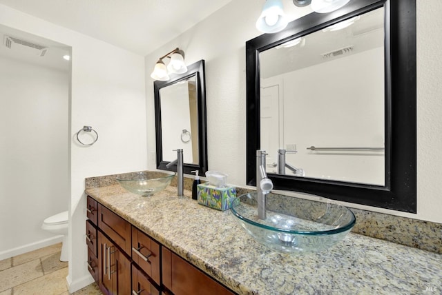 full bath with double vanity, visible vents, toilet, and a sink