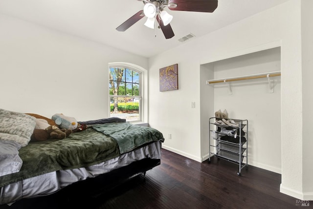 bedroom featuring baseboards, wood finished floors, visible vents, and a ceiling fan