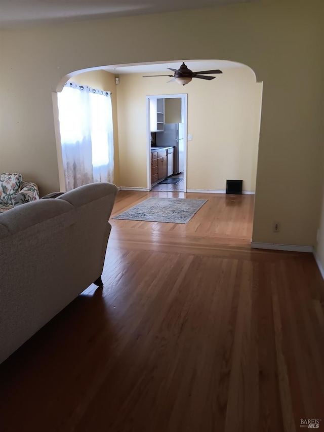living room with arched walkways, ceiling fan, and wood finished floors
