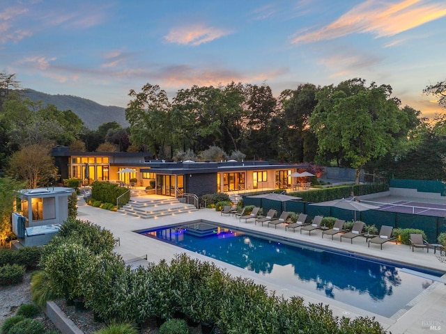 back of property featuring a jacuzzi, fence, a mountain view, a patio, and a fenced in pool