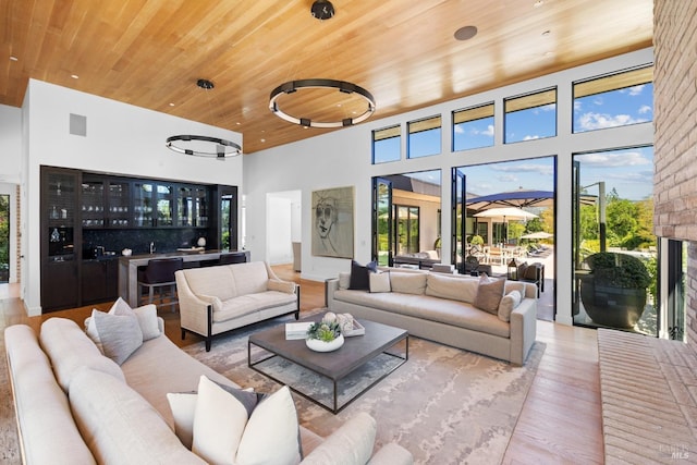 living room with a high ceiling, wood finished floors, visible vents, wooden ceiling, and bar