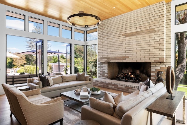 living room featuring wood ceiling, a fireplace, and a healthy amount of sunlight