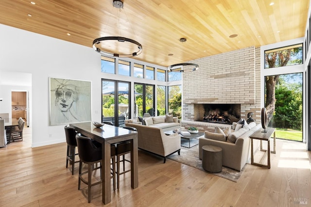 living room with a brick fireplace, light wood-type flooring, a wealth of natural light, and wooden ceiling