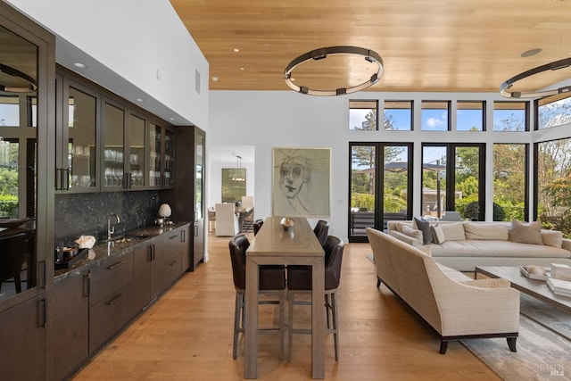 interior space featuring wood ceiling, a towering ceiling, light wood-style flooring, wet bar, and recessed lighting