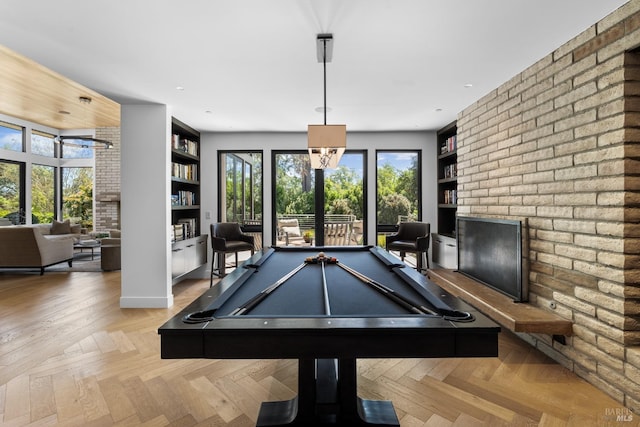 recreation room featuring brick wall, a brick fireplace, built in features, and billiards