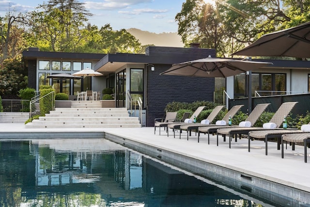 back of house with an outdoor pool, a patio, and stairway