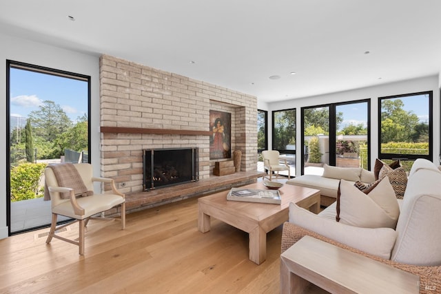 living room featuring recessed lighting, light wood-style floors, and a brick fireplace