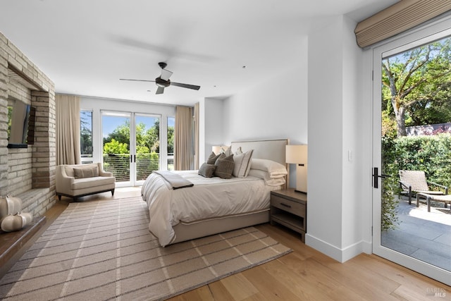 bedroom with multiple windows, light wood-type flooring, baseboards, and access to outside