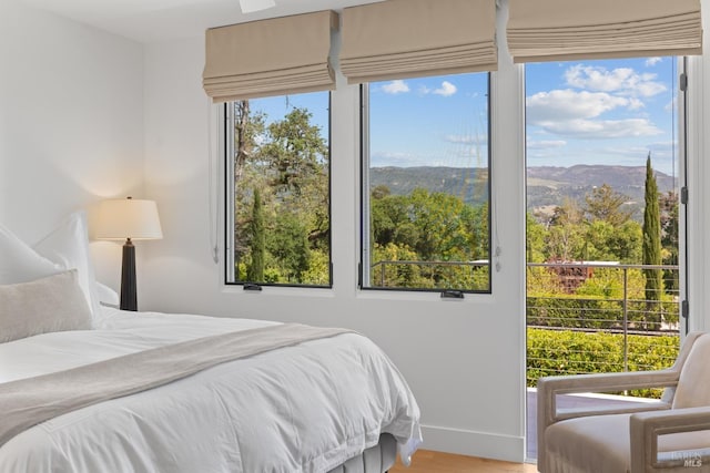 bedroom with baseboards, wood finished floors, and a mountain view