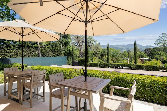 view of patio / terrace with outdoor dining area, a mountain view, and fence
