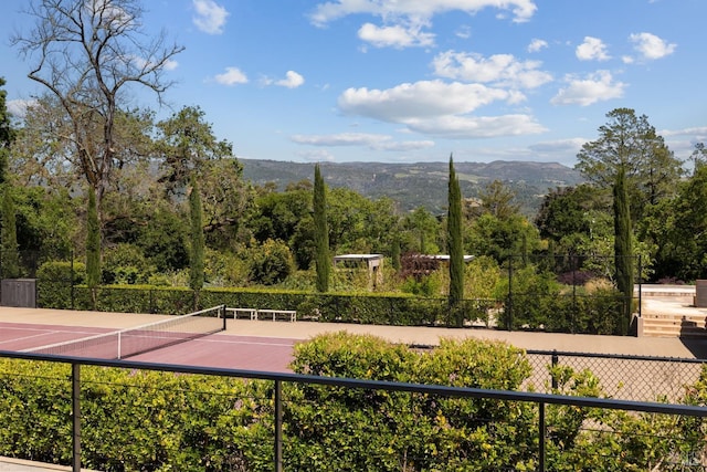 view of community with a tennis court, fence, and a mountain view