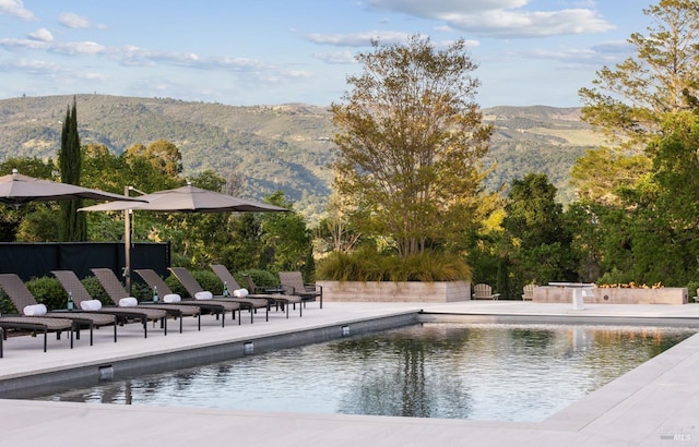 outdoor pool with a mountain view and a patio