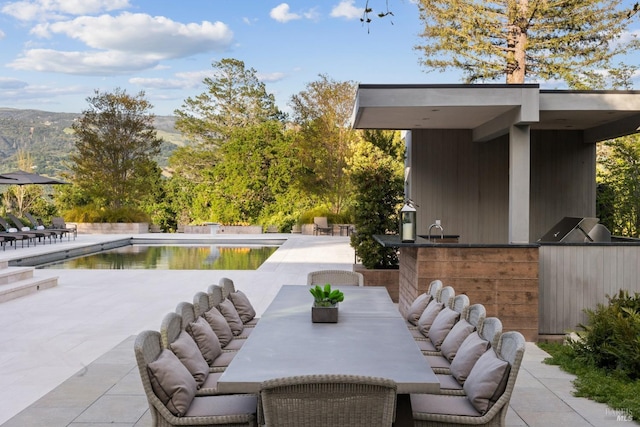 view of patio featuring outdoor dining space, area for grilling, and an outdoor pool