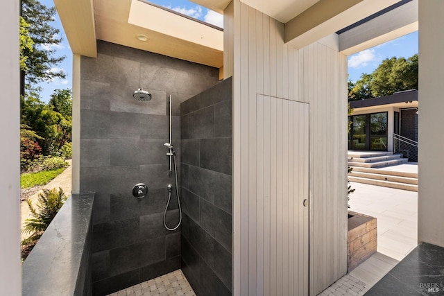 bathroom with a tile shower and a skylight