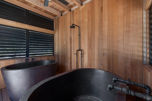 interior details with a ceiling fan, wood walls, and beam ceiling