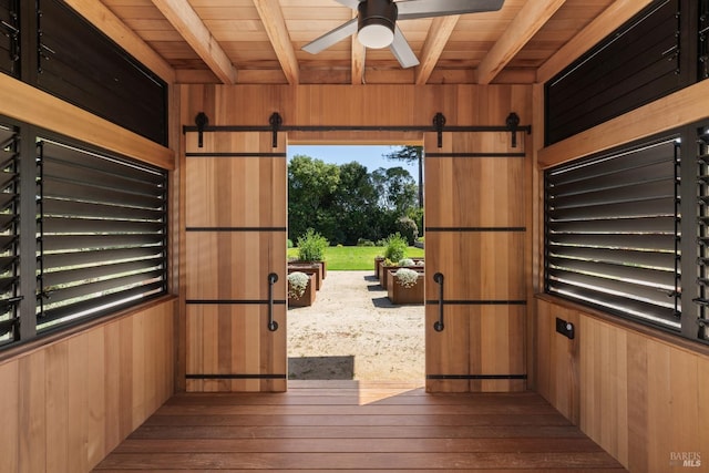 entryway with beam ceiling, wood walls, wooden ceiling, and ceiling fan