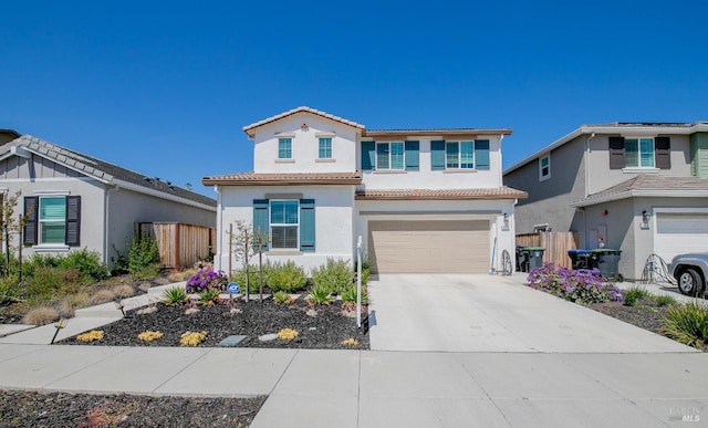 traditional-style home featuring a tile roof, concrete driveway, an attached garage, fence, and stucco siding