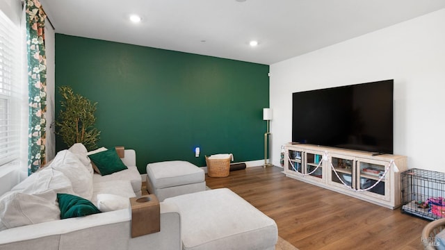 living room featuring recessed lighting, an accent wall, and wood finished floors
