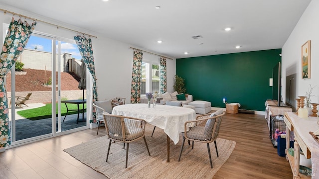 dining area featuring recessed lighting, an accent wall, wood finished floors, and visible vents