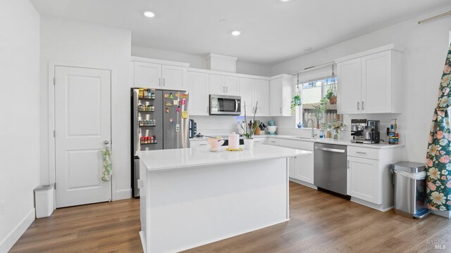 kitchen with white cabinets, appliances with stainless steel finishes, wood finished floors, and a sink