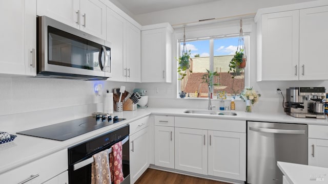 kitchen featuring light countertops, white cabinetry, a sink, and black appliances