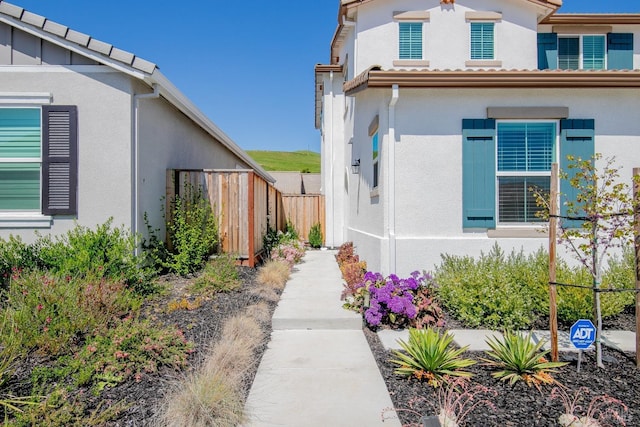 view of side of property featuring stucco siding and fence