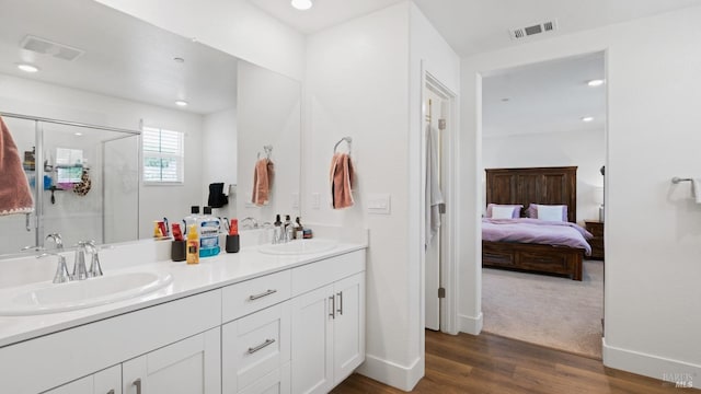 ensuite bathroom featuring wood finished floors, a sink, visible vents, and a stall shower