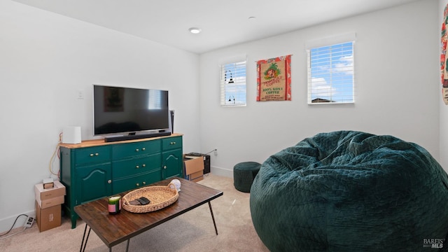 living room featuring baseboards, a healthy amount of sunlight, and light colored carpet